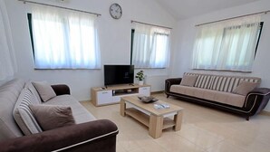 A modern living room with a brown sofa, a beige sofa, a coffee table, and a TV on a wooden stand. - Bili dvori by Interhome (Trilj)