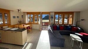 A spacious living area with a kitchen, dining table, and a large sofa. - Am Gilsbach 2 by Interhome (Adelboden)