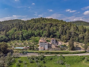 A rural property with two stone buildings, a swimming pool, and a forested hillside.