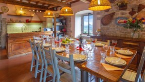 A dining area with wooden tables and chairs, a stone wall with decorative elements, and hanging wicker lamps. - Villa Monteloro by Interhome (Florence)