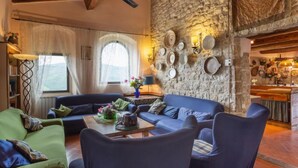 A cozy living room with a stone wall, blue sofas, and a wooden ceiling. - Villa Monteloro by Interhome (Florence)