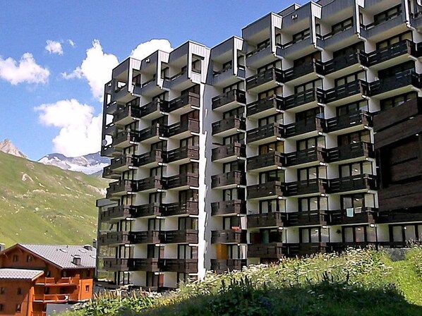 Un hôtel à plusieurs étages, doté de balcons, situé dans un cadre montagneux.