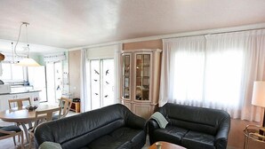 Een woonkamer met twee zwarte leren banken, een houten salontafel en een kast met glazen deuren.