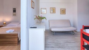 A bedroom with a bed, bedside table, and a small desk with a vase of flowers. There are three framed pictures on the wall. - Apartment Nika by Interhome (Umag)
