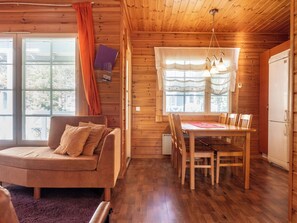 Interior acogedor de una cabaña con piso de madera, un sofá, una mesa de comedor con sillas y una zona de cocina.
