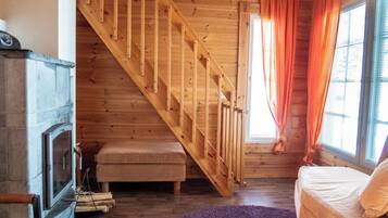 Eine Holztreppe führt zu einem Schlafzimmer auf dem Dachboden, mit einem Bett und einem fenster mit Vorhängen.