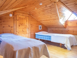 A wooden cabin with two beds, a door, and a framed picture on the wall.