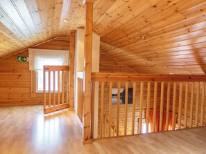 Interior de madera con techo inclinado, una escalera a la vista y una ventana con vista al agua.