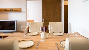 Un coin repas avec une table en bois mise pour quatre personnes, comprenant des assiettes, des couverts et des verres à vin.