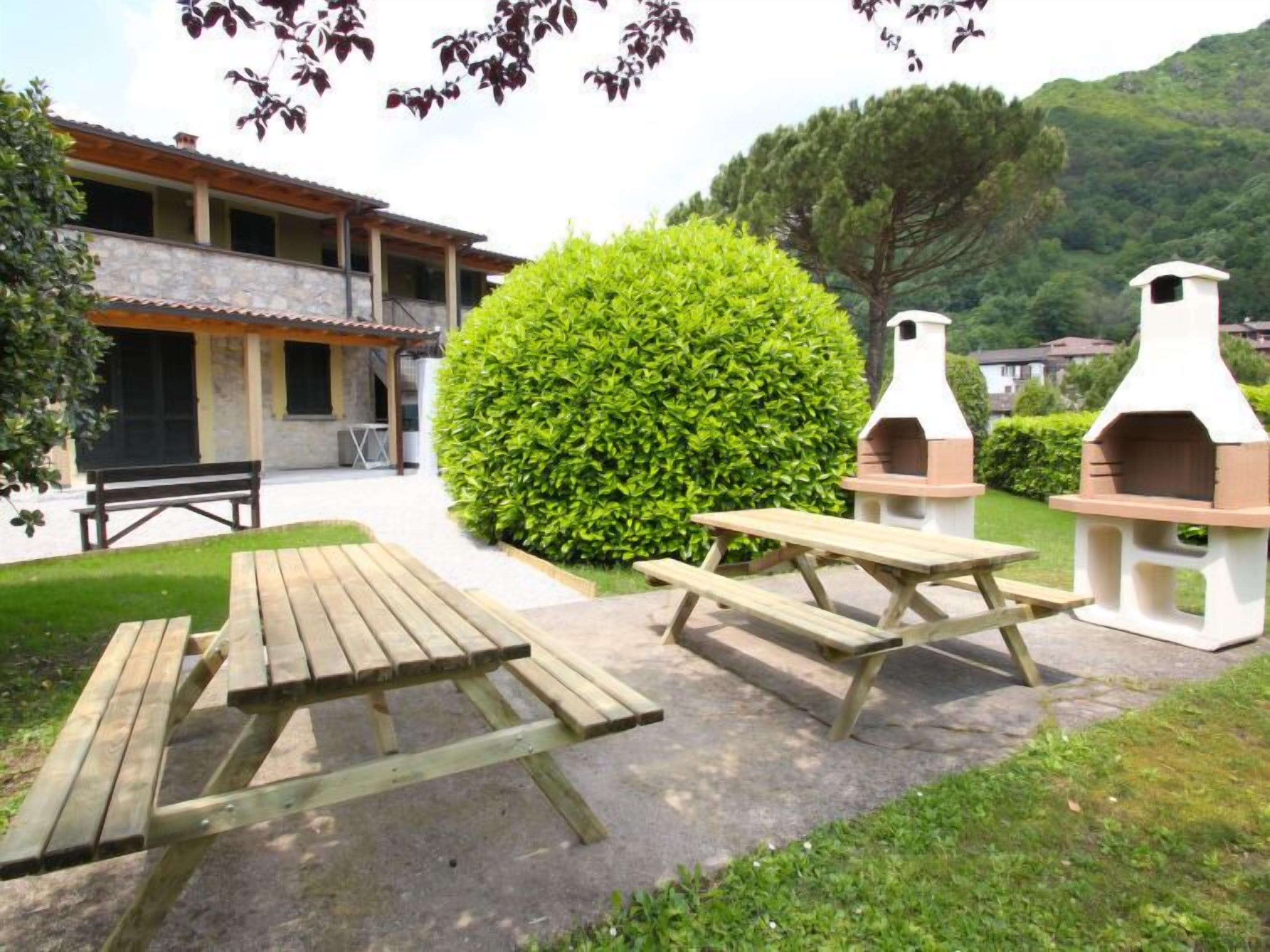 An outdoor patio area with picnic tables and two outdoor ovens.