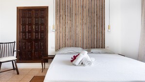 Camera d'albergo con un letto, un armadio in legno, una sedia e un pannello parete a listelli di legno.