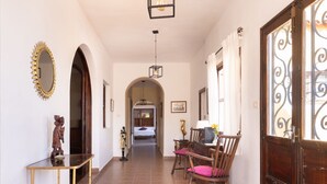 Un corridoio con un tavolo e sedie in legno, uno specchio e una porta con decorazioni in ferro battuto.