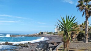Una spiaggia con rocce, palme e un cielo azzurro limpido.