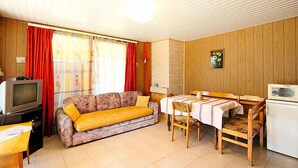 Un espacio habitable compacto con sofá, mesa de comedor y kitchenette.
