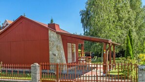 Un edificio rojo con fachada de piedra, un porche cubierto y un jardín cercado.