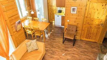 Interior acogedor de una cabaña de madera con comedor, kitchenette y sofá.