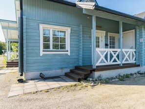 A blue building with a porch, steps, and a door.