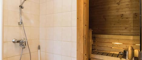 Uma sauna de madeira com área de chuveiro revestida em azulejos.
