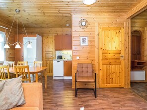 A wooden interior with a dining area, kitchen, and a cozy seating space.