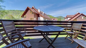 Une terrasse en bois avec une table ronde et quatre chaises en bois, le tout entouré d’une clôture en bois.