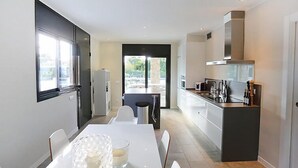 Una cocina moderna con comedor, ventanas amplias y vistas a zonas verdes.