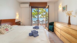 A hotel room with a bed, a desk, a dresser, a ceiling fan, and a view of the outside. - Es Clot by Interhome (Alcúdia)