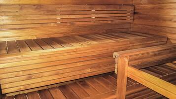 Een houten sauna bank met een lattenstructuur, een houten frame en een raam erboven.