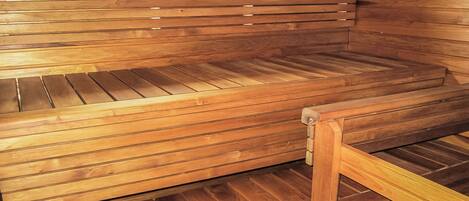 A wooden sauna bench with a slatted design, a wooden frame, and a window above it.
