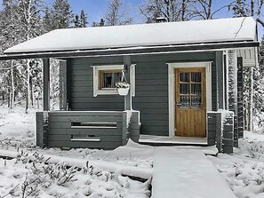 En liten, envåningsstuga med en veranda, en dörr och ett fönster.