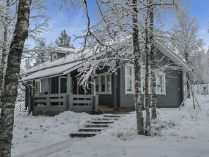 A cabin with a wooden porch, surrounded by snow-covered trees. - Kallentupa by Interhome (Kuusamo)