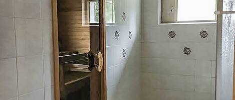 Um quarto com piso de azulejos, porta de madeira e uma janela.