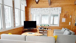 Un acogedor interior de cabaña con un sofá, un televisor y un escritorio de madera.