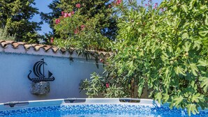 A swimming pool with clear blue water, surrounded by a tiled wall with a decorative anchor symbol. - Vacation home Bakić by Interhome (Pula/Krnica)