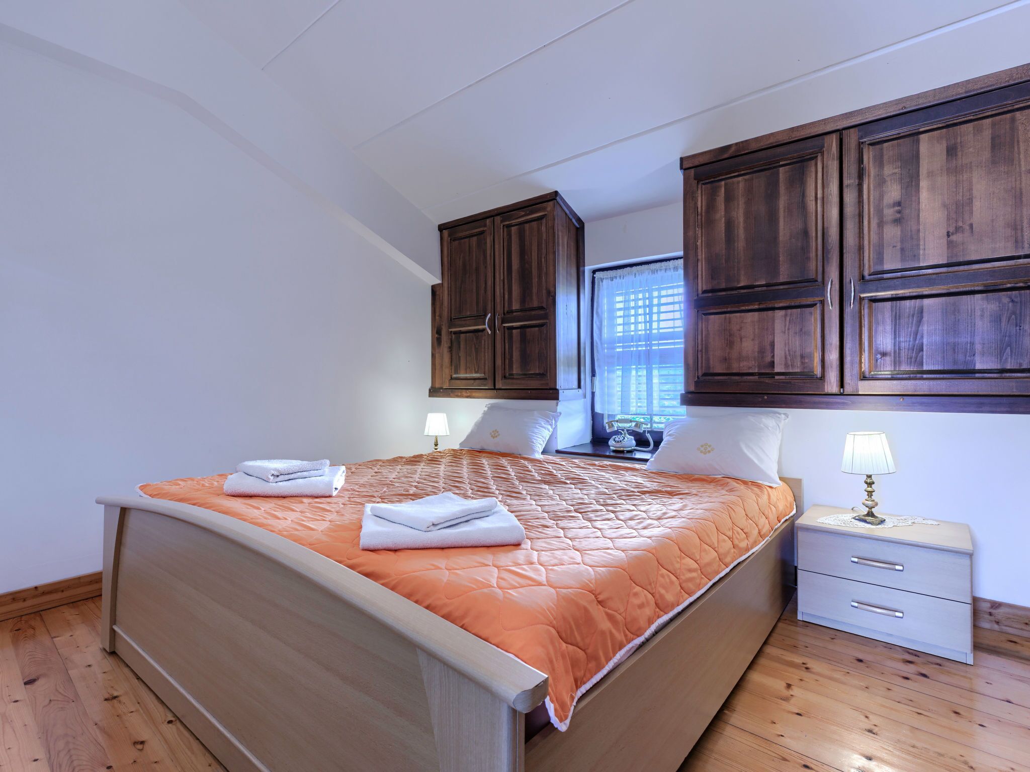 A neatly made bed with a quilt, two bedside lamps, and a nightstand with a lamp.