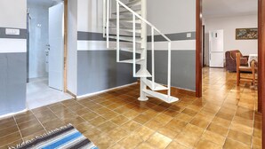A spacious living area with a white spiral staircase, a dining area with a table and chairs, and a kitchen with a refrigerator. - Vacation home Bakić by Interhome (Pula/Krnica)