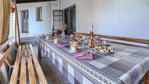A dining area with a long table set for a meal, featuring a checkered tablecloth, plates, glasses, and a bottle. - Vacation home Bakić by Interhome (Pula/Krnica)