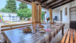 A dining area with a long table set for a meal, a view of the outdoors, and a wooden ceiling. - Vacation home Bakić by Interhome (Pula/Krnica)