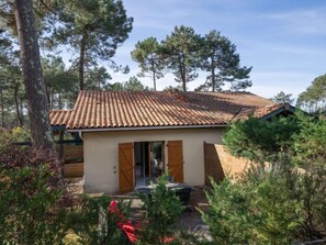 Un piccolo edificio a un piano con tetto in tegole, circondato da alberi e vegetazione.