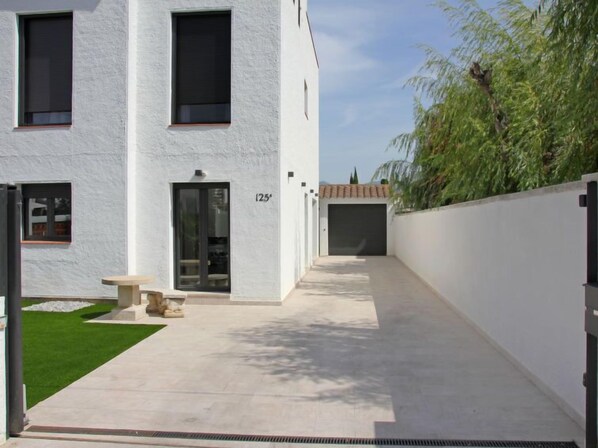 Un edificio moderno con fachada blanca, número 125, que cuenta con un acceso cubierto y un pequeño espacio de esparcimiento al aire libre.