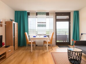 A modern room with a dining table, two chairs, a TV, a cabinet, and a sofa.