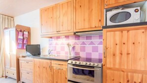 Een keuken met houten kastjes, een magnetron, een fornuis en een spoelbak.