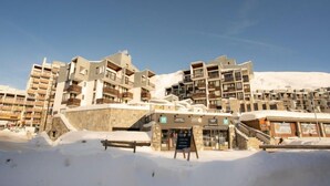 Een hotel bedekt met sneeuw, met meerdere balkons en een stenen gevel.