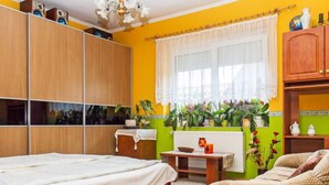A bedroom with a bed, a wooden wardrobe, a window with curtains, a radiator, and a green wall. - Vacation home Colore by Interhome (Balatonmariafurdo)