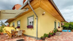 A yellow building with a tiled patio, outdoor seating, and potted plants. - Vacation home Colore by Interhome (Balatonmariafurdo)