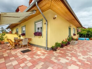 A yellow building with a tiled patio, outdoor seating, and potted plants. - Vacation home Colore by Interhome (Balatonmariafurdo)