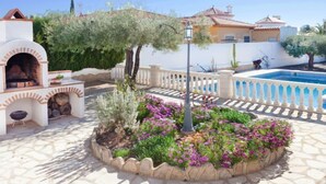 A patio with a barbecue area, a swimming pool, and a garden with flowers. - Rustical Mont Roig by Interhome (Miami Platja)