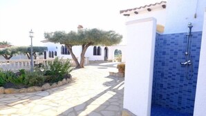 A stone pathway leading to a building with a blue-tiled shower area. - Rustical Mont Roig by Interhome (Miami Platja)