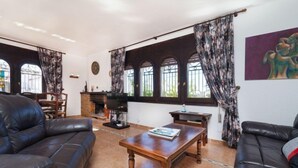 A living room with leather sofas, a wooden coffee table, a fireplace, and large windows with curtains. - Rustical Mont Roig by Interhome (Miami Platja)