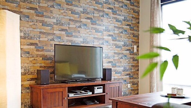 A living room with a brick wall, a flat-screen TV on a wooden stand, and a coffee table. - Witthuus-Baltrum by Interhome (Norddeich)
