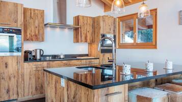 Een moderne keuken met houten kastjes, een centraal eiland, roestvrijstalen apparatuur en hanglampen.